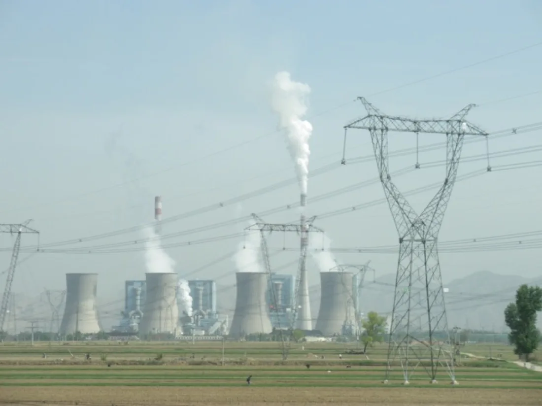 A coal-fired power station with cooling towers emitting steam.