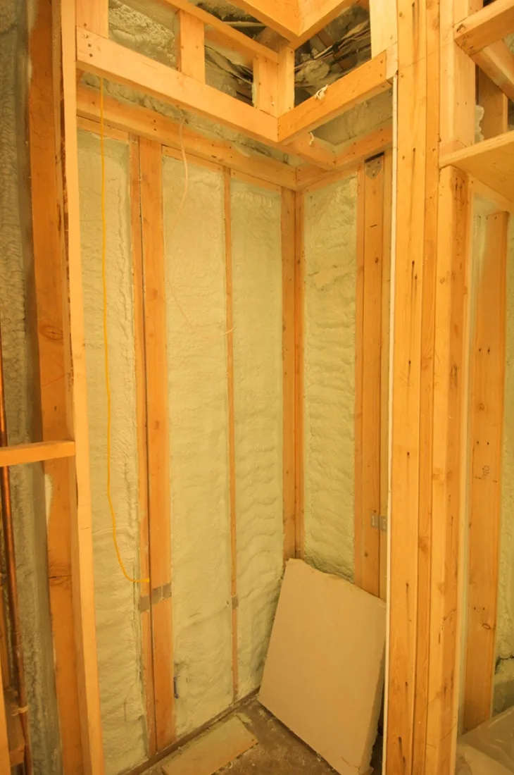 A timber-framed wall cavity filled with sprayed foam insulation.