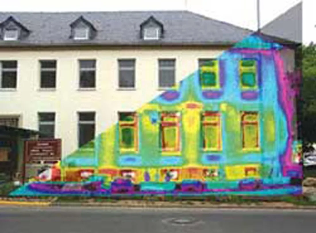 A photograph of a building with a thermal image overlaid on half of it, showing hot spots in yellow and red around the windows and doors.